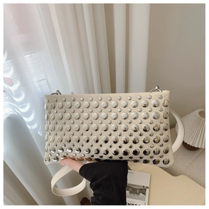 Detail of cream white punk crossbody bag featuring silver metallic studs and slim strap