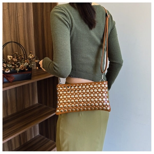 Detail view of brown punk style rivet shoulder bag with silver studs and long strap