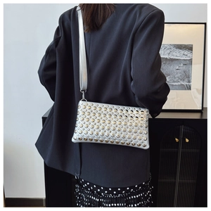 Close-up of a silver punk crossbody bag with metal rivets on a black blazer model