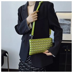 Detail of lime green leather bag with silver rivets styled with a black blazer