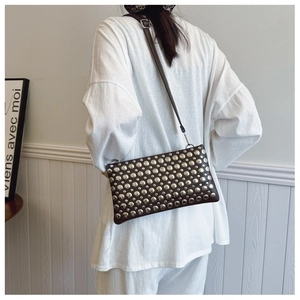 Detail of dark brown leather crossbody bag featuring silver round stud decorations