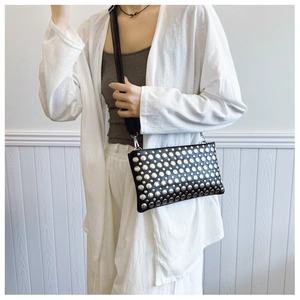 Detail of black PU leather crossbody bag with silver metal rivets and rock style finish