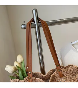 Close-up of durable brown leather straps and metallic rivets on hand-woven crochet tote bag