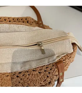 Detail of metal zipper closure and white cotton lining on woven straw tote bag