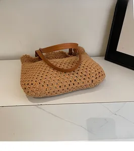 Detail of hand-woven hollow pattern and brown leather handles on a summer tote bag