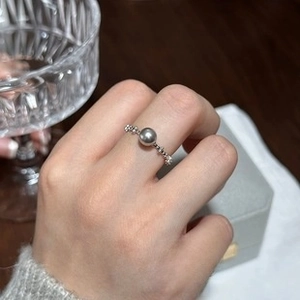 Detailed view of silver flower chain ring with grey pearl on model finger