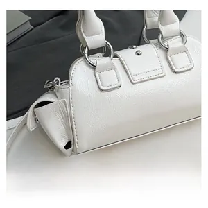 Détail d'un sac à main blanc en cuir texturé avec boucle argentée et fermoir à pression