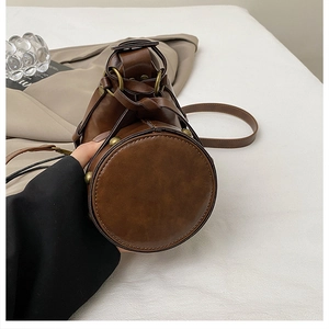 Close-up of the round bucket bag base with vintage metal rivets and premium brown PU leather