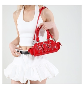 Détail du sac à main en cuir verni rouge avec rivets punk argentés et bandoulière réglable