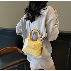 Vue arrière du mannequin portant un sac seau en cuir jaune mat avec bandoulière large