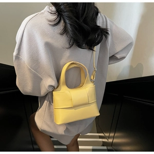 Sac seau jaune vif tendance avec nœud porté par un mannequin dans un escalier