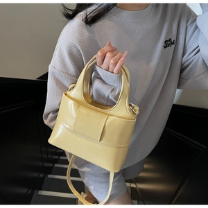 Détail d'un sac seau jaune crème avec nœud porté par un mannequin dans un cadre décontracté