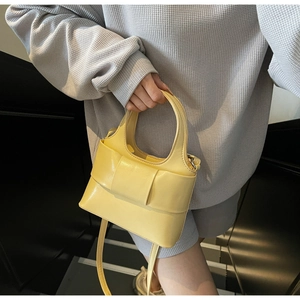 Détail d'un mini sac à main jaune à nœud avec poignée et bandoulière sur le mannequin