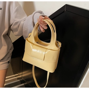 Détail d'un sac à main jaune crème en cuir avec sangle décorative et bandoulière