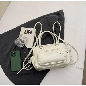 Détail du sac à main blanc en PU avec nœud 3D posé sur un blazer gris de style chic