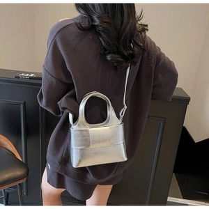 Détail du sac seau argenté métallisé avec design de nœud et bandoulière réglable