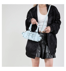 Détail d'un sac à main bleu clair style motard avec boucles argentées et bandoulière amovible