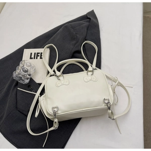 Détail du sac à dos en similicuir crème avec nœuds décoratifs et anneaux métalliques