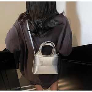 Détail d'un sac seau métallisé argenté avec nœud abstrait porté par un mannequin