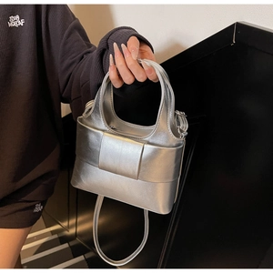 Détail de la surface argentée texturée et du nœud élégant sur ce sac à main bandoulière