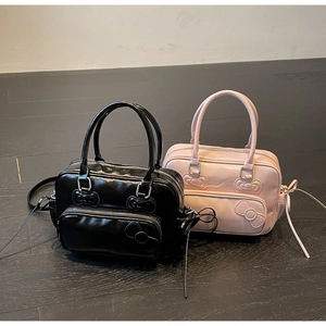 Détail du sac en cuir verni brillant avec motifs de nœuds en relief et rubans latéraux