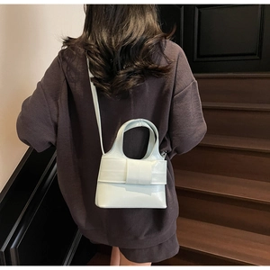Petit sac seau bleu menthe avec un grand nœud 3D, porté par un mannequin en tenue décontractée