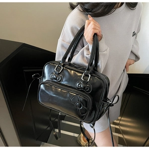 Detail of a black glossy PU backpack with 3D bows and a convenient front zipper pocket