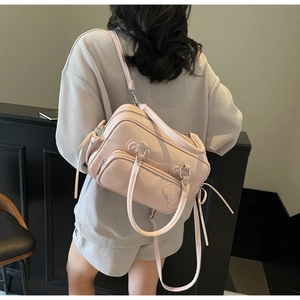 Detail of pink bow handbag showing dual handles and adjustable strap on a model