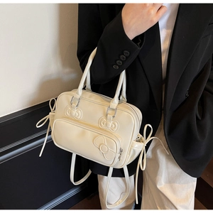 Close-up of cream PU leather backpack with embossed 3D bows and silver zipper detail