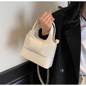 Détail d'un sac seau blanc crème avec un grand nœud décoratif et texture en cuir brillant
