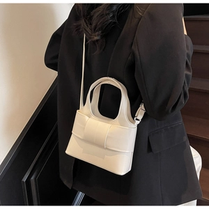 Gros plan du sac seau en cuir blanc élégant avec nœud décoratif et bandoulière amovible