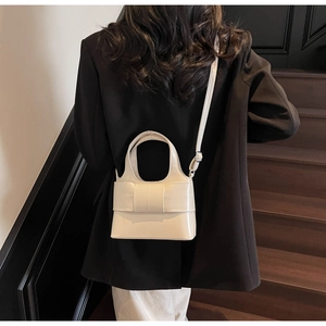 Détail du sac seau blanc en cuir brillant avec grand nœud et bandoulière réglable