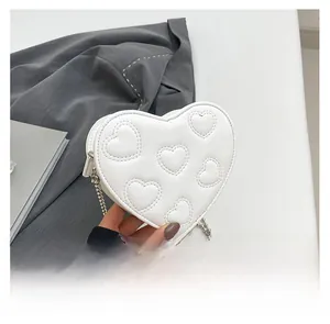 Detailed view of white heart-shaped bag with quilted faux leather and silver bead chain