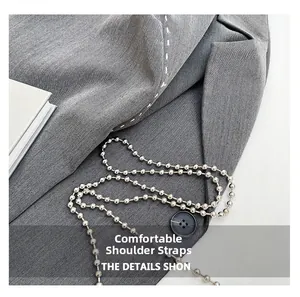 Detail of grey twill fabric texture with white decorative stitching and silver ball chain