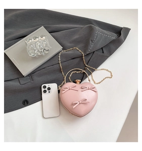 Detailed close-up of pink heart-shaped clutch bag with elegant bows and metal handle