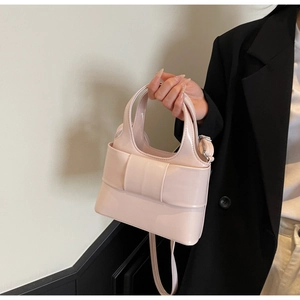 Détail d'un sac à main en cuir verni rose avec décoration de nœud et bandoulière réglable