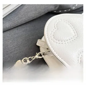 Detail of white heart-shaped bag showing glossy cracked texture and quilted heart pattern