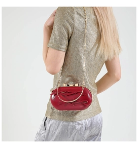 Macro detail of red glossy evening bag with decorative bows and golden chain strap