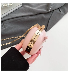 Close-up of pink evening clutch bag with gold metal frame and stylish bow detail