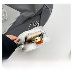 Interior capacity of white heart-shaped bag with lipstick and notepad on grey suit fabric