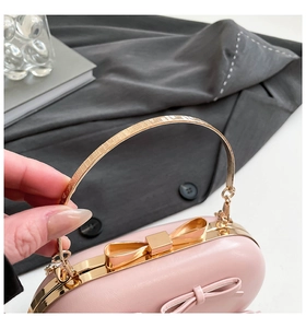 Detailed close-up of pink leather evening bag featuring a gold metal bow clasp and handle