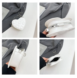 Detailed views of white heart-shaped mini crossbody bag with silver chain and quilted patterns