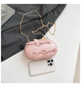 Detailed close-up of pink oval evening bag with bow knots and golden ring handle