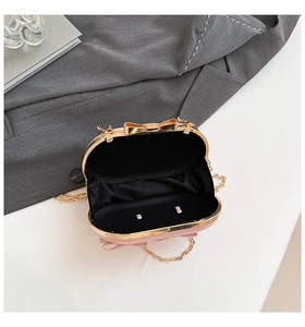 Detail of pink evening clutch bag with gold bow clasp and elegant chain strap inside