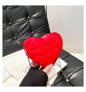 Close-up of red heart-shaped quilted handbag with glossy finish and silver chain strap