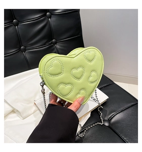 Detail view of heart-shaped green crossbody bag featuring embossed embroidery and silver chain