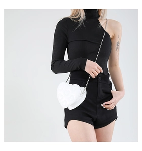 Detail view of the white heart-shaped bag with embossed patterns and silver chain strap