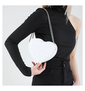Close-up of white heart-shaped crossbody bag with quilted leather and silver chain strap