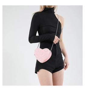 Detail of pink heart-shaped chain bag with embossed hearts worn by a model