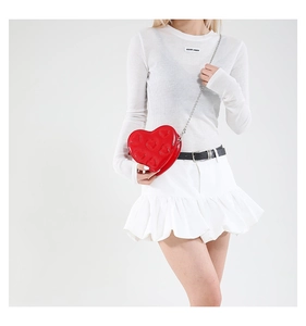 Detail of red heart-shaped crossbody bag with quilted heart stitching and silver chain